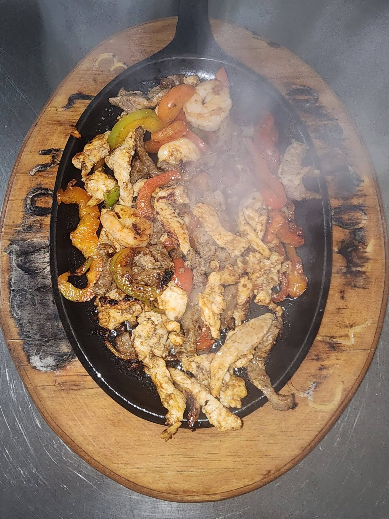 Sizzling mixed fajitas with steak, chicken, shrimp and peppers on a hot skillet