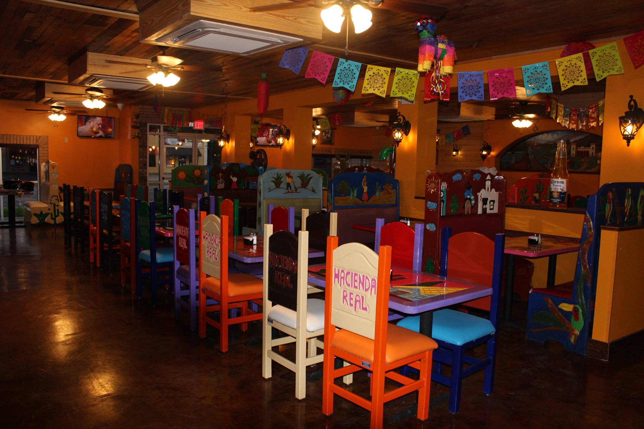 Colorful hand-painted chairs and papel picado banners inside Hacienda Real
