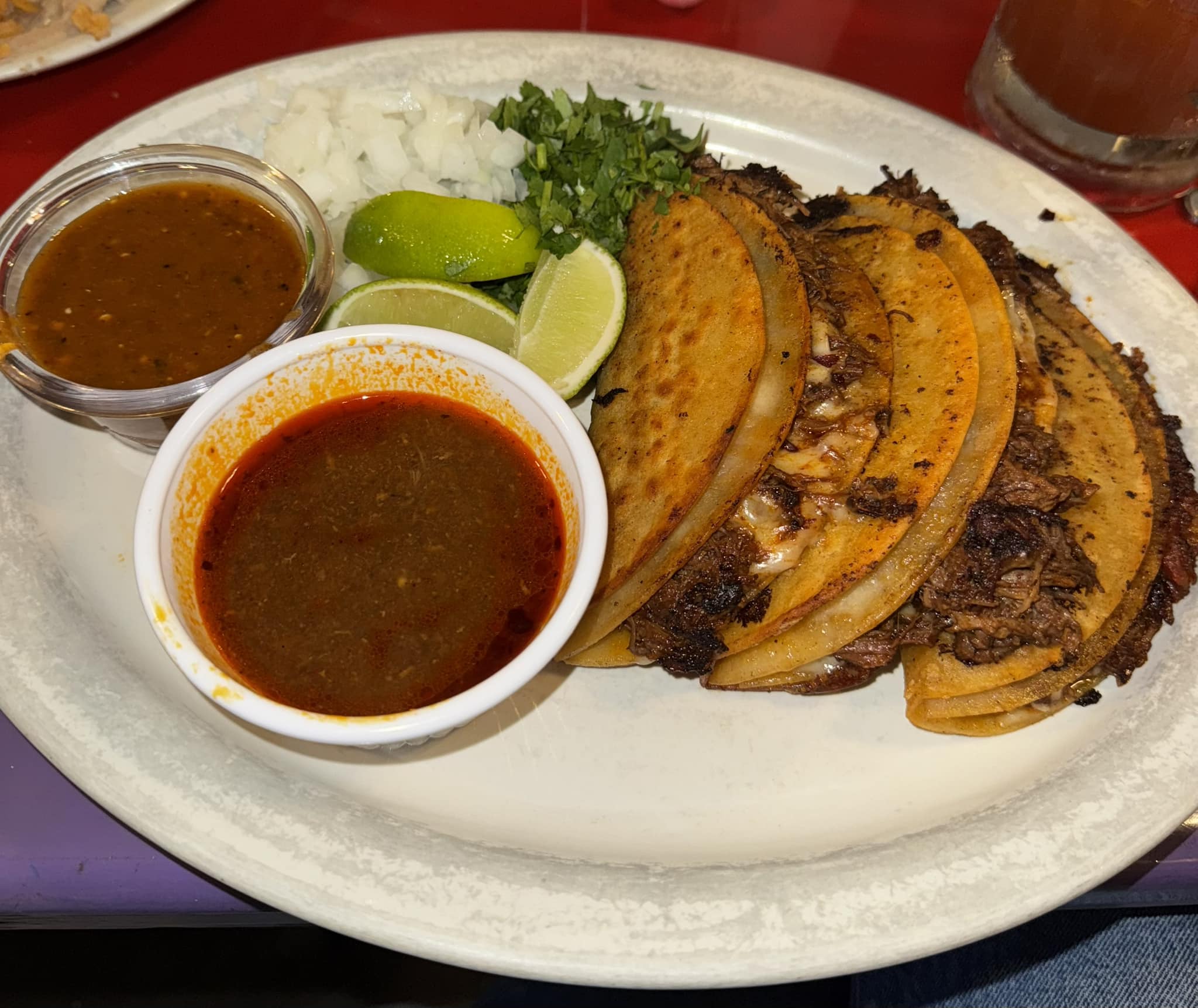 Quesabirria tacos with a cup of rich beef consomé for dipping