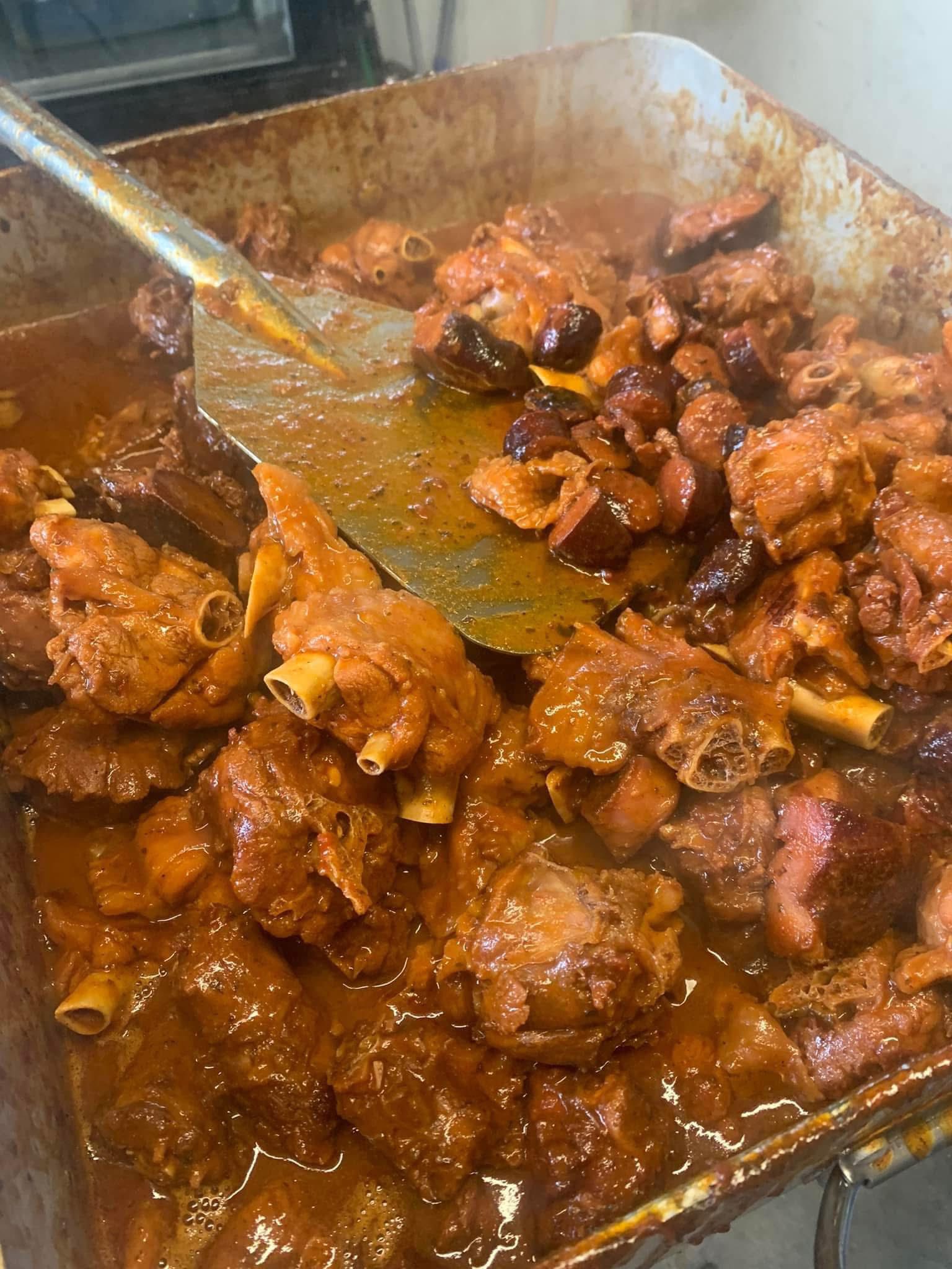A large pan of slow-smothered Cajun meat with a bay leaf