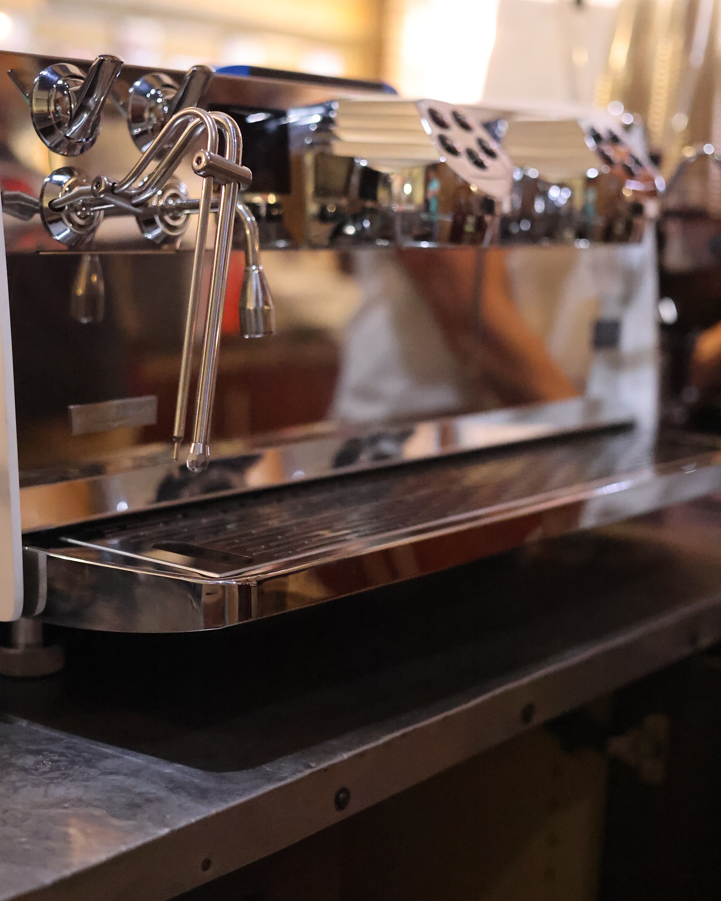 Polished chrome espresso machine on the cafe bar, catching the light.