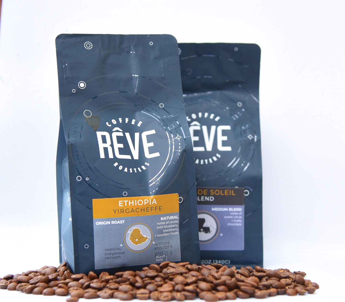 Two bags of Rêve Coffee Roasters beans — an Ethiopia Yirgacheffe single origin — standing over a scatter of roasted coffee beans.